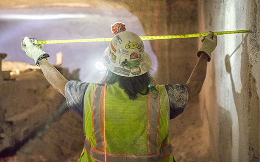 Miner checking dimensions with measuring tape